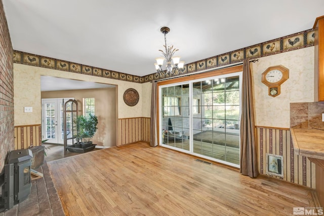 unfurnished dining area featuring a wealth of natural light, a chandelier, hardwood / wood-style flooring, and french doors