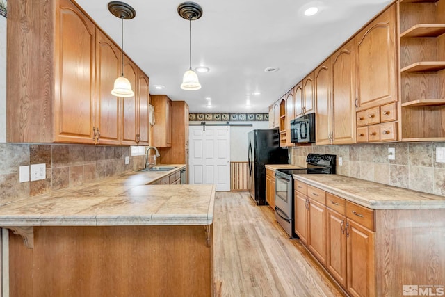 kitchen featuring kitchen peninsula, light hardwood / wood-style flooring, black appliances, sink, and decorative light fixtures