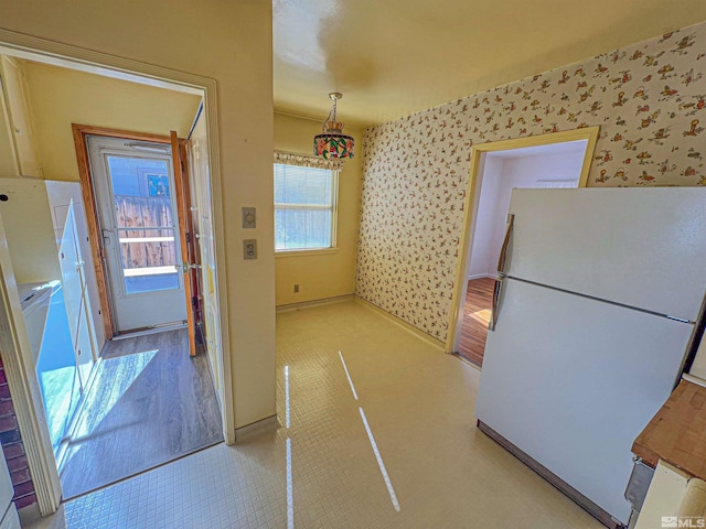 kitchen with white fridge, a healthy amount of sunlight, and decorative light fixtures