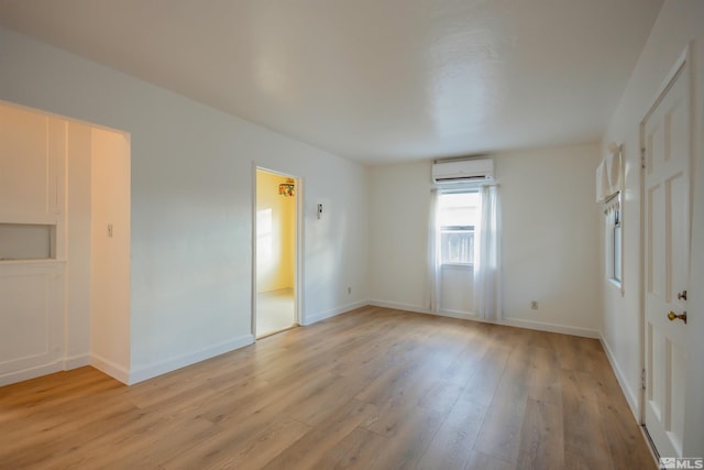 empty room with an AC wall unit and light hardwood / wood-style flooring