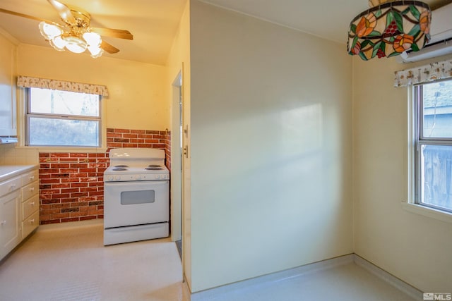 kitchen with brick wall, white range with electric cooktop, plenty of natural light, and ceiling fan