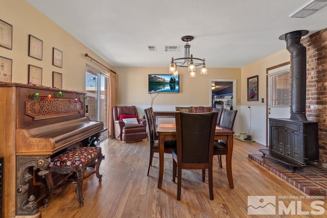 dining space with a chandelier, light hardwood / wood-style floors, and a wood stove