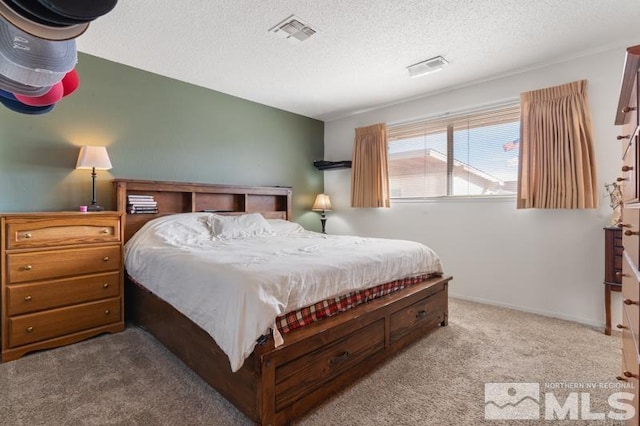 bedroom with a textured ceiling and light colored carpet