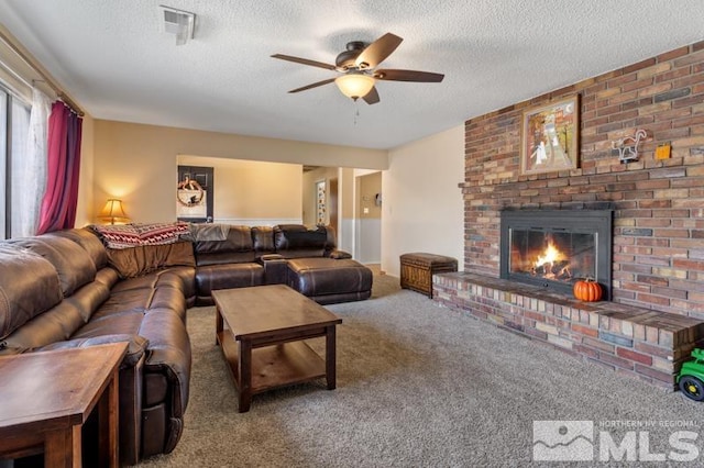 living room with a textured ceiling, carpet flooring, a fireplace, and ceiling fan