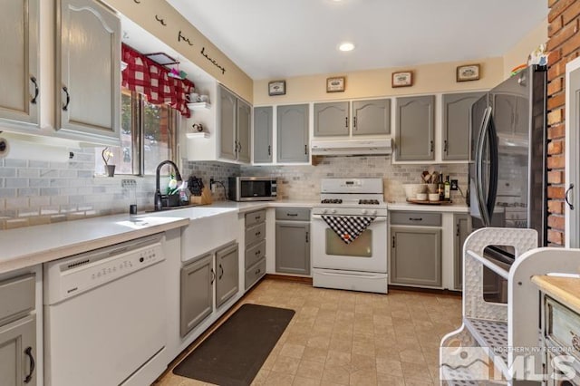 kitchen featuring white appliances, decorative backsplash, sink, and gray cabinetry