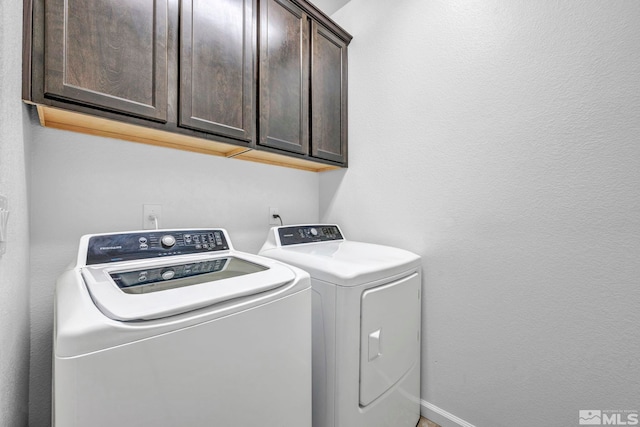 laundry area featuring washer and clothes dryer and cabinets