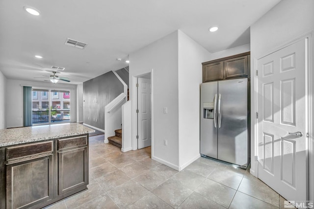 kitchen featuring light stone counters, stainless steel fridge, dark brown cabinetry, and ceiling fan