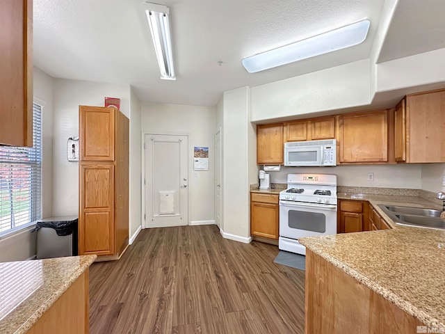 kitchen featuring dark hardwood / wood-style flooring, white appliances, and sink