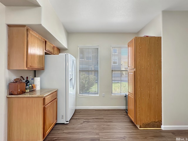 kitchen with white refrigerator, light stone countertops, and light hardwood / wood-style floors