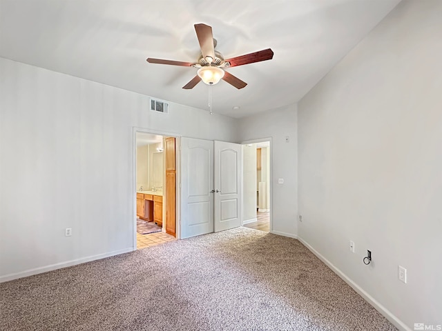 unfurnished bedroom with ceiling fan, ensuite bathroom, and light colored carpet