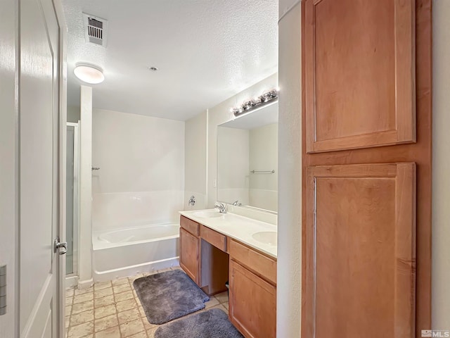 bathroom with a bathing tub, vanity, and a textured ceiling