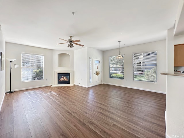 unfurnished living room with ceiling fan and dark wood-type flooring