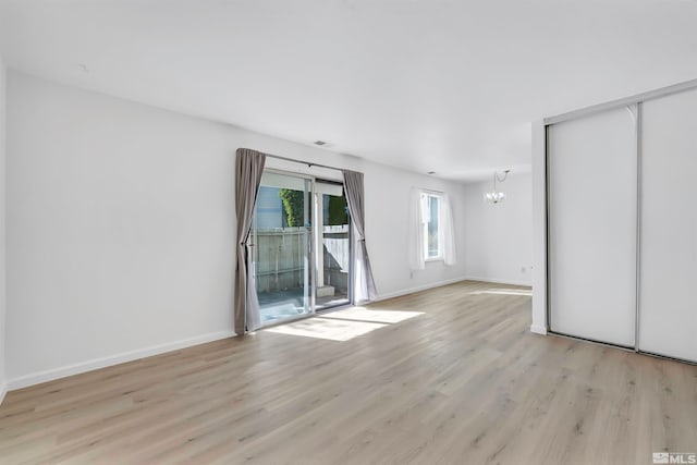 empty room featuring light hardwood / wood-style floors and a chandelier