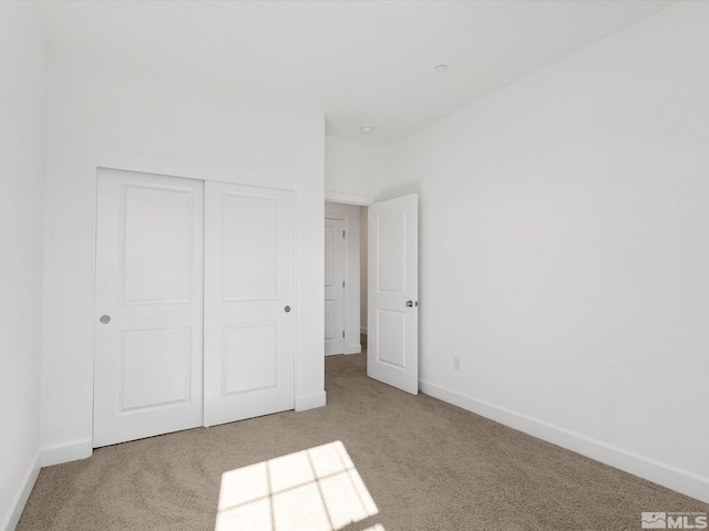 unfurnished bedroom featuring a closet and light colored carpet