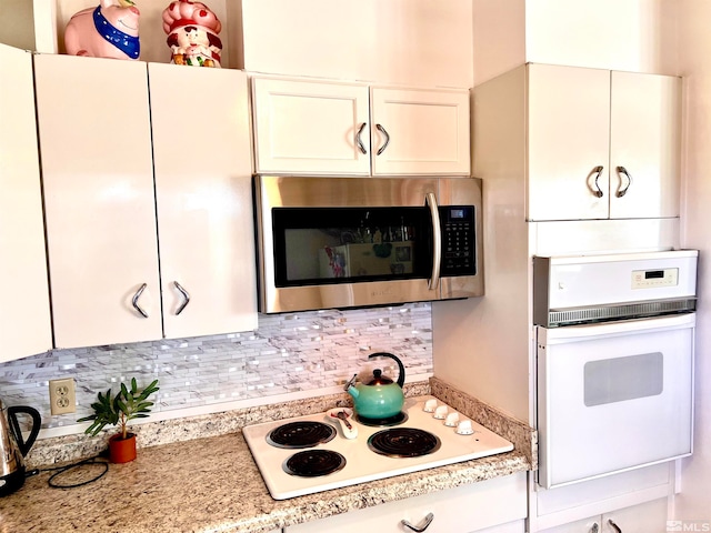 kitchen with decorative backsplash, white cabinetry, light stone countertops, and white appliances