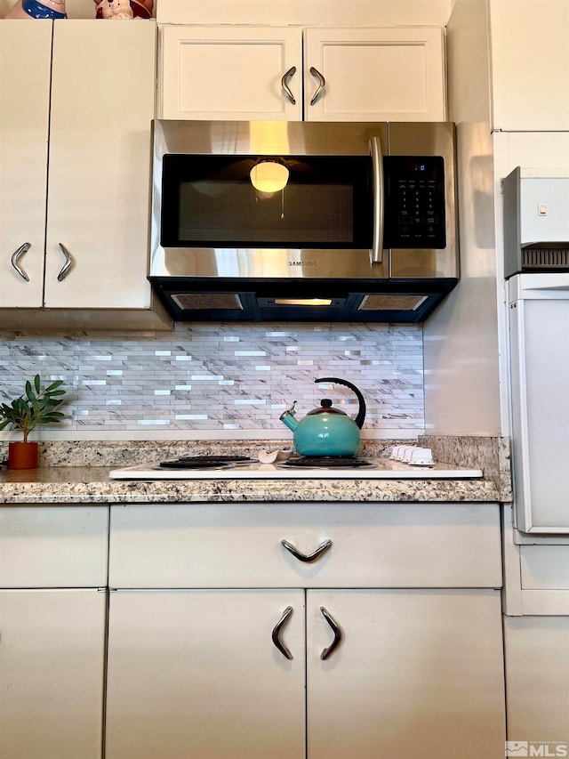 kitchen featuring white gas cooktop, white cabinets, and backsplash