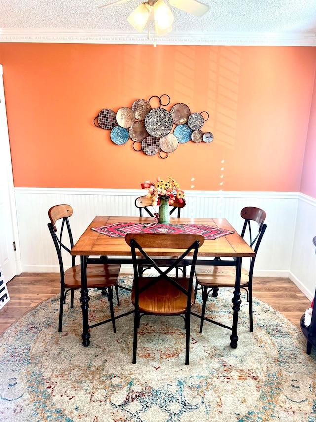 dining space featuring crown molding, hardwood / wood-style flooring, a textured ceiling, and ceiling fan