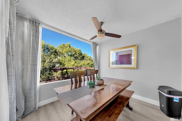 dining area featuring a textured ceiling, a ceiling fan, baseboards, and light wood-type flooring