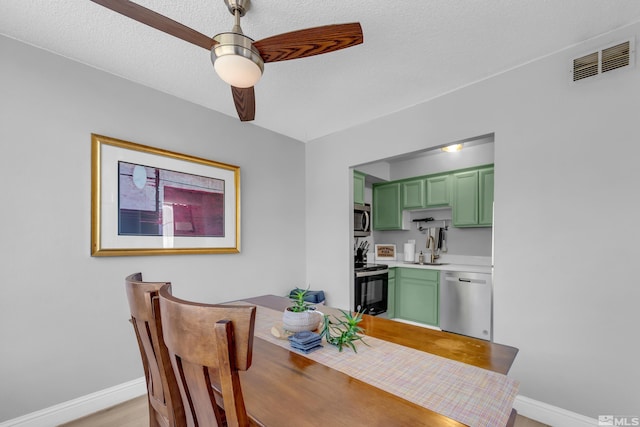 dining room with baseboards, visible vents, ceiling fan, and a textured ceiling