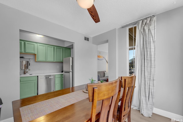 dining room featuring a textured ceiling, visible vents, baseboards, and light wood-style floors