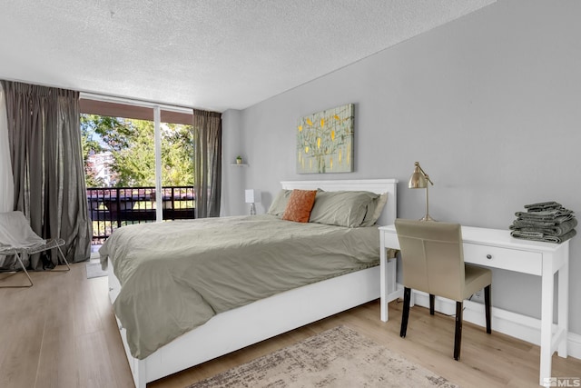 bedroom featuring light hardwood / wood-style floors, access to outside, and a textured ceiling