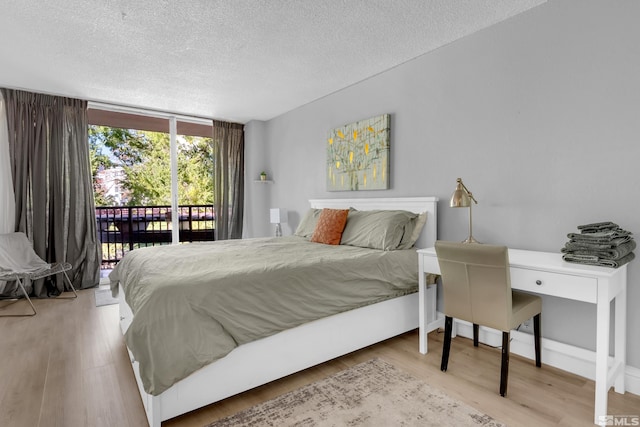 bedroom with access to exterior, wood finished floors, and a textured ceiling