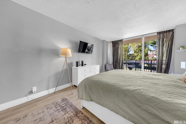 bedroom with a textured ceiling, light wood-type flooring, access to outside, and baseboards