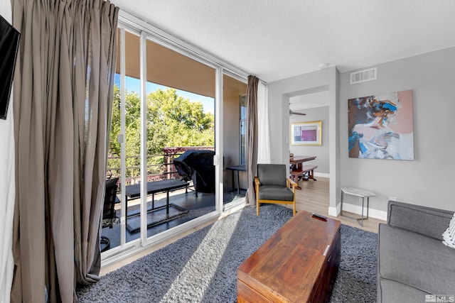 living room featuring a ceiling fan, visible vents, baseboards, a textured ceiling, and wood finished floors