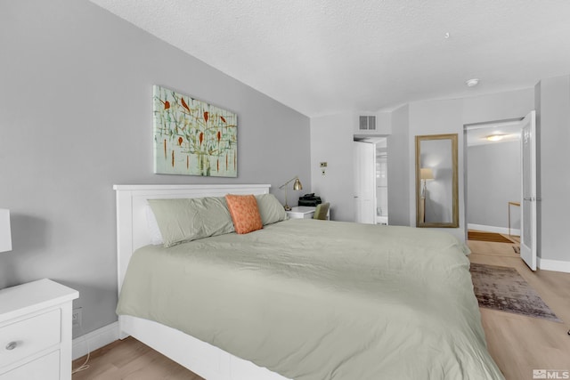 bedroom featuring a textured ceiling and light hardwood / wood-style flooring