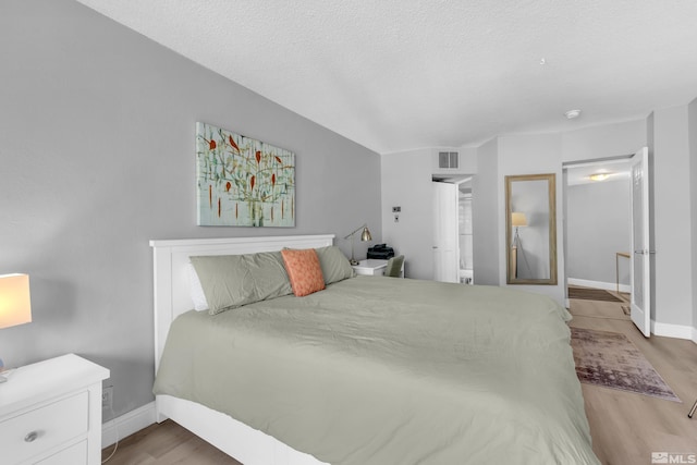 bedroom featuring baseboards, visible vents, and wood finished floors