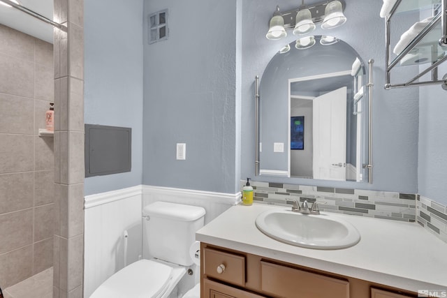 bathroom featuring vanity, toilet, and a tile shower