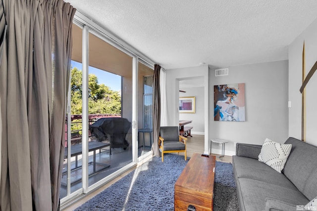 living room with a textured ceiling, visible vents, wood finished floors, and baseboards