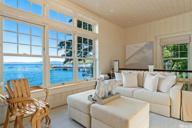 carpeted living room with a water view and wooden ceiling