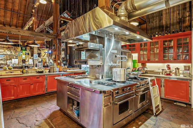 kitchen with wood ceiling, stainless steel counters, vaulted ceiling with beams, range with two ovens, and decorative light fixtures