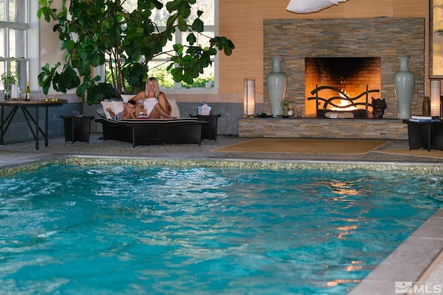 view of swimming pool featuring a patio area and an outdoor living space with a fireplace