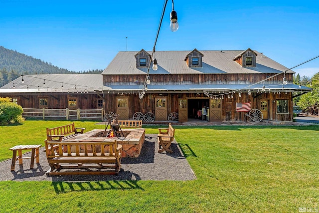 rear view of house with an outdoor fire pit, a mountain view, a yard, and a patio