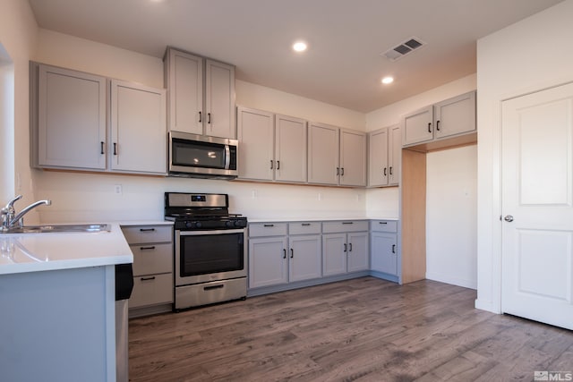 kitchen with gray cabinets, sink, appliances with stainless steel finishes, and dark wood-type flooring