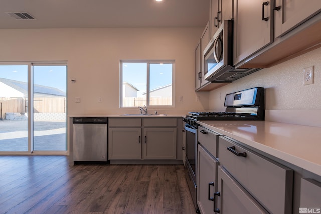 kitchen with gray cabinets, stainless steel appliances, sink, and dark hardwood / wood-style flooring