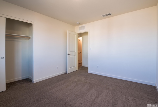 unfurnished bedroom with a closet and dark colored carpet