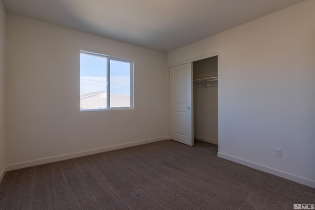 unfurnished bedroom with dark colored carpet and a closet