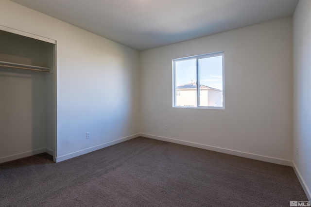 unfurnished bedroom featuring a closet and dark colored carpet