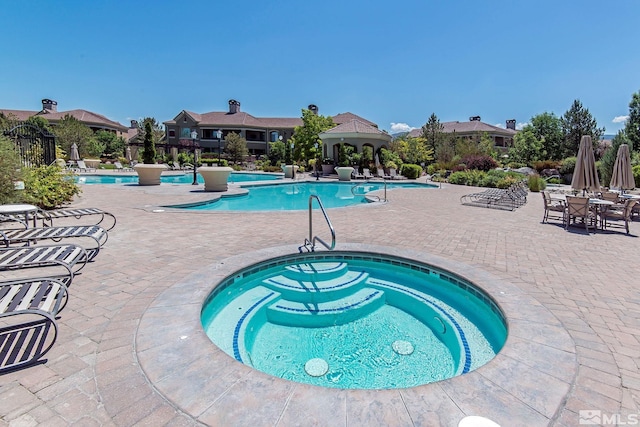 view of swimming pool featuring a hot tub and a patio area