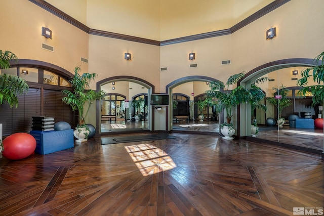 workout area with parquet flooring, crown molding, and a towering ceiling