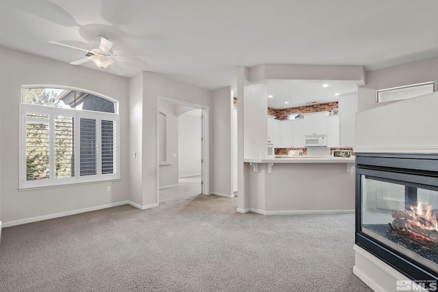 carpeted living room with ceiling fan and a multi sided fireplace