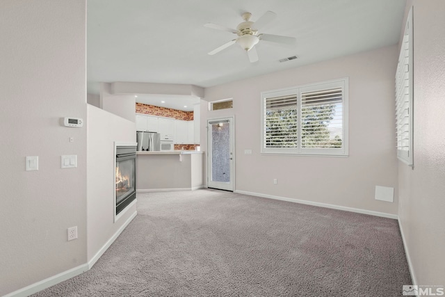 unfurnished living room featuring ceiling fan and light carpet