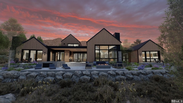 back house at dusk with outdoor lounge area and a patio area