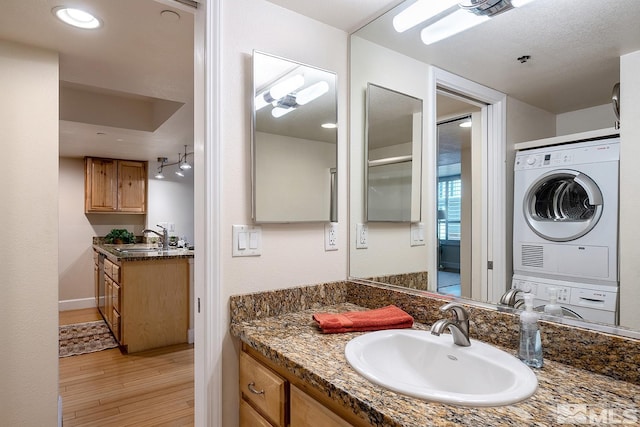 bathroom featuring vanity, stacked washer and dryer, and hardwood / wood-style floors