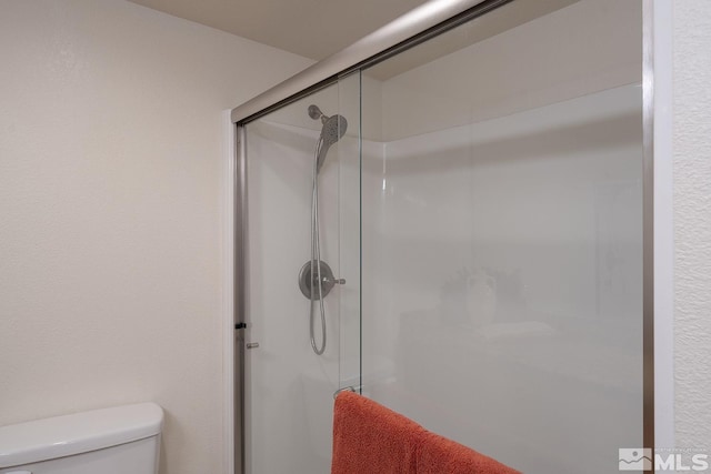 bathroom with a shower with shower door and toilet