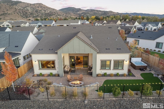 back house at dusk featuring a patio, a mountain view, and a fire pit