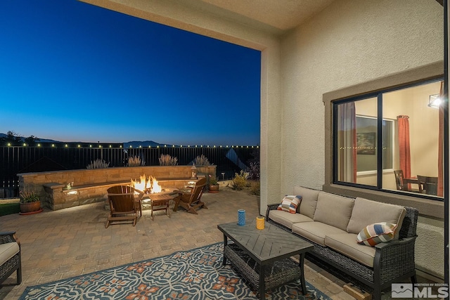 patio terrace at dusk with an outdoor living space with a fire pit